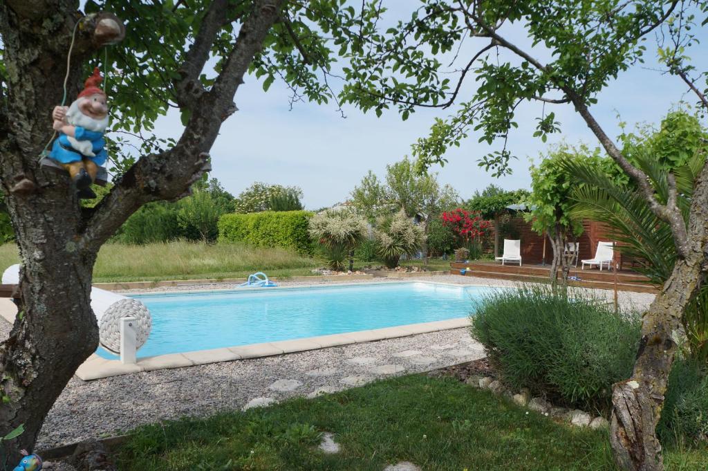 un enfant assis sur un arbre à côté d'une piscine dans l'établissement cottage blanchou, à Galapian