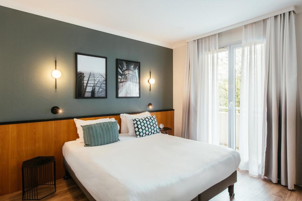 une chambre avec un grand lit et une grande fenêtre dans l'établissement Aparthotel Adagio La Défense Le Parc, à Courbevoie