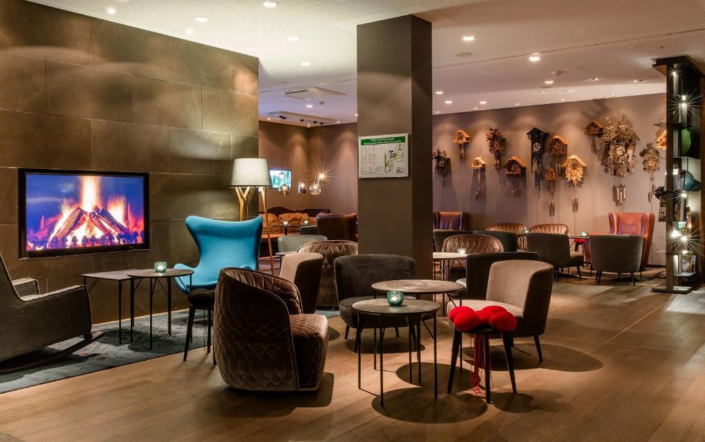 eine Lobby mit einer Bar mit Stühlen und Tischen in der Unterkunft Motel One Freiburg in Freiburg im Breisgau