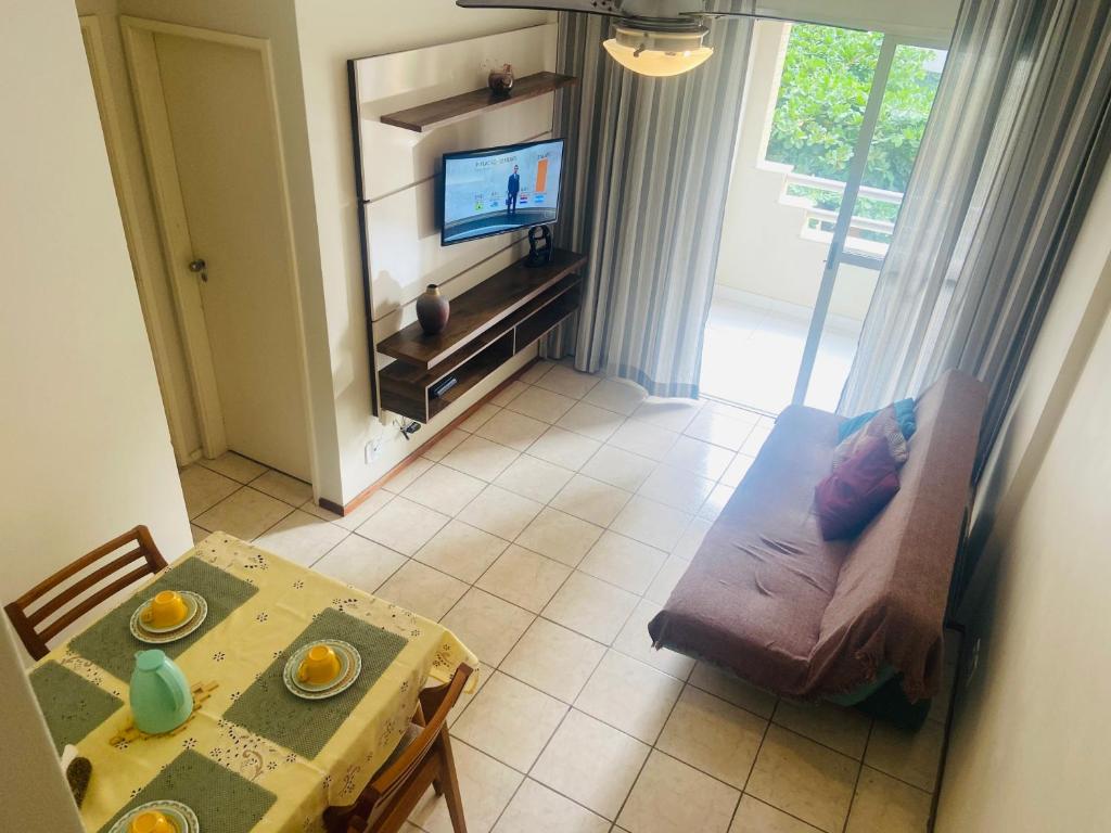 a living room with a table and a television at Poucos passos do mar na Praia da Costa in Vila Velha