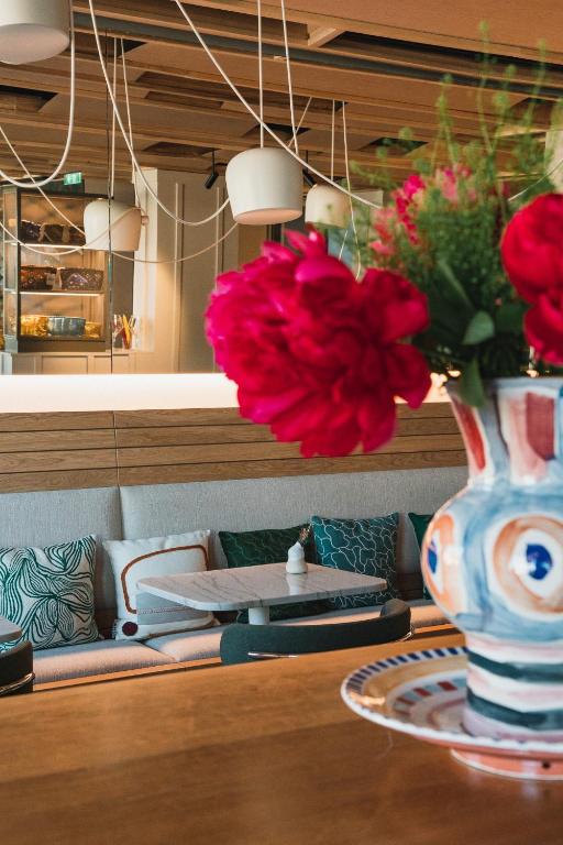 a vase with red flowers sitting on a table at Hôtel de La Plage in Biarritz