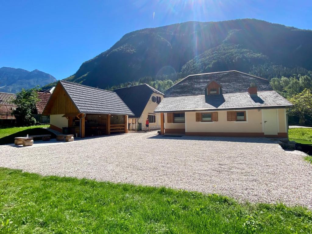 a house with a gravel driveway in front of a mountain at FAMILY HOUSE Pri Kovaču in Soča