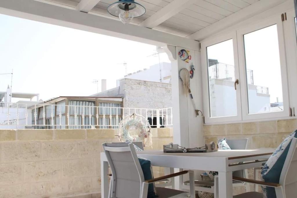 ポリニャーノ・ア・マーレにあるSogno D'Amare, casa con vista e terrazzo privatoの窓付きの客室で、白いテーブルと椅子が備わります。
