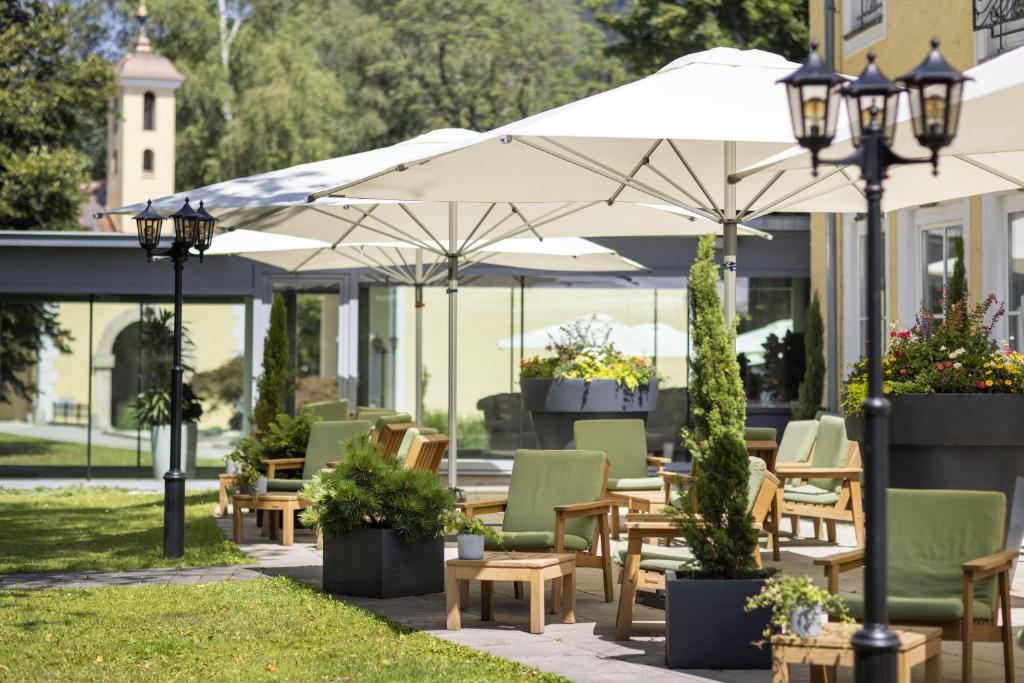 a patio with tables and chairs and umbrellas at ARCOTEL Castellani Salzburg in Salzburg