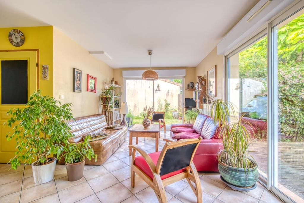 un salon avec un canapé rouge et des plantes dans l'établissement Maison calme et vue foret, à Andernos-les-Bains