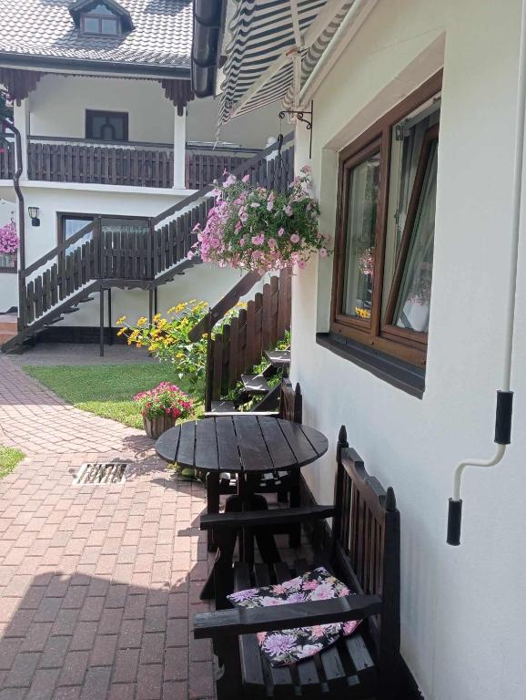 a table and benches next to a building with flowers at Pokój dwuosobowy Sosnowa in Krasnobród