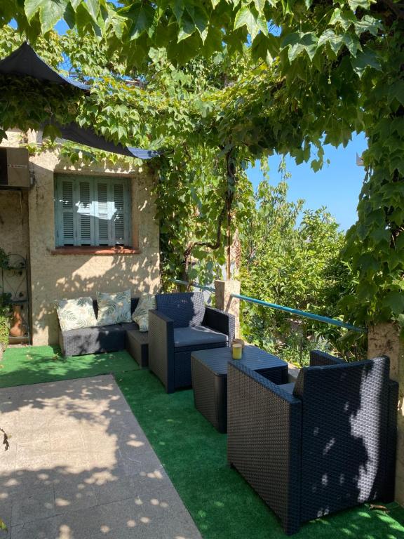 une terrasse avec des canapés et des chaises sous un arbre dans l'établissement L'Oustalet, à Nice