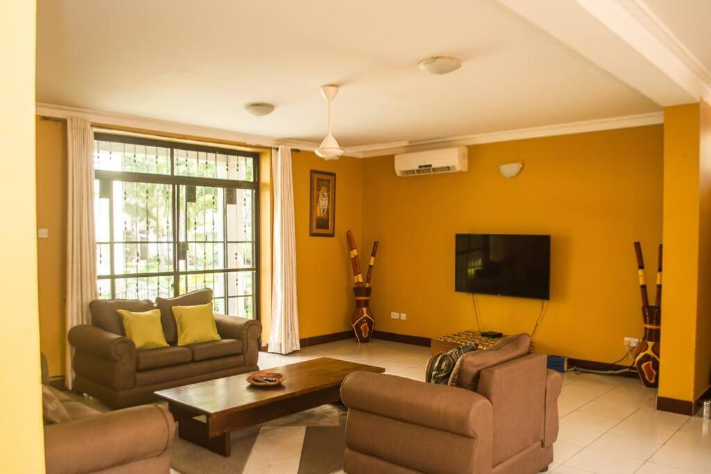 Una sala de estar con dos sofás y un televisor de pantalla plana. en LEN Apartments, en Dar es Salaam