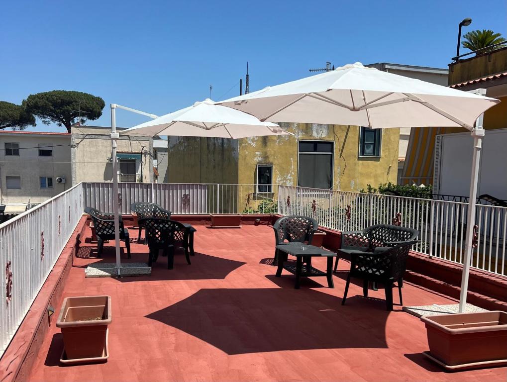 a patio with tables and chairs and umbrellas at Sunset B&B Pompei in Pompei