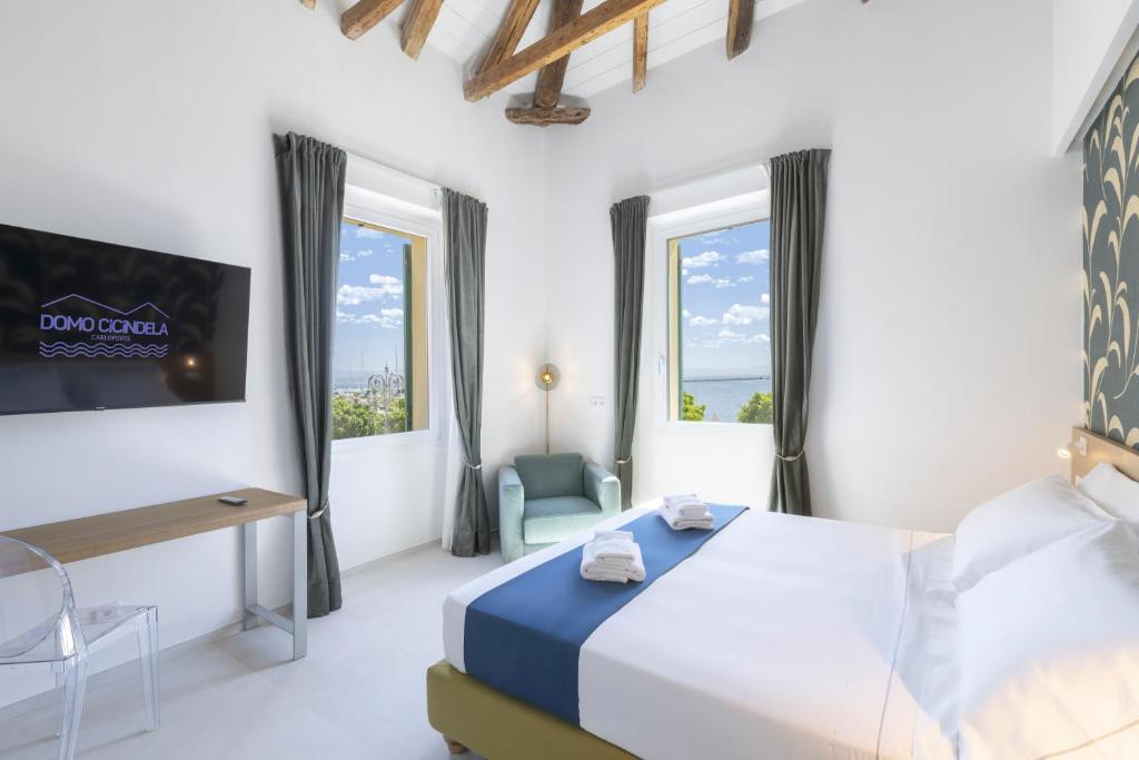 a bedroom with a bed and a tv and windows at Domo Cicindela Boutique Rooms Centro Carloforte in Carloforte