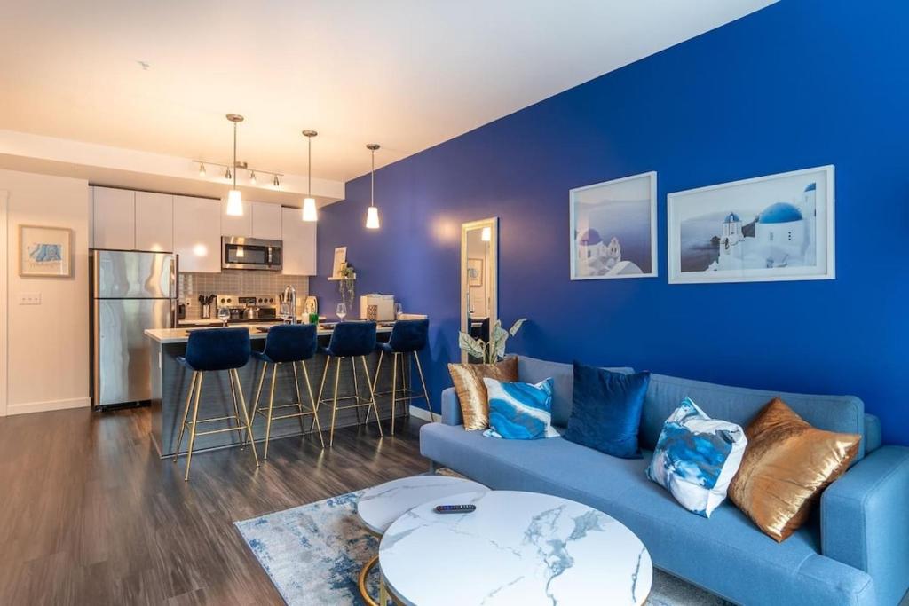 Una sala de estar con un sofá azul y una cocina. en Paid Garage Parking- King Bed-balcony Wd 55" Tv, en Tacoma