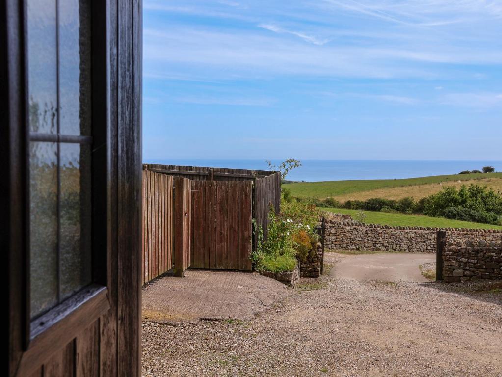 an open door to a gate in a field at Dairy Cottage in Staintondale