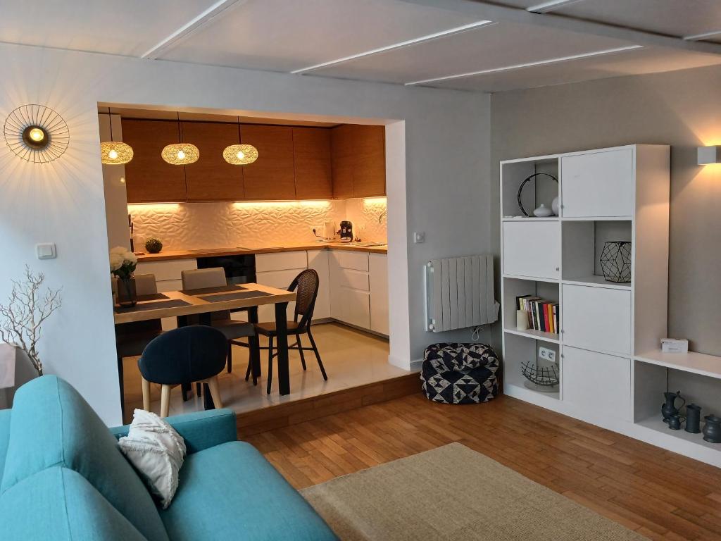 a living room with a blue couch and a kitchen at Maison cosy et jardin verdoyant in Drancy