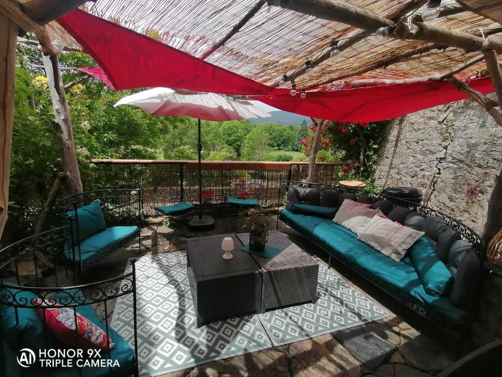 une terrasse avec un canapé bleu et un parasol rouge dans l'établissement Maison au coeur du village de la Salvetat sur Agout, à La Salvetat-sur-Agout