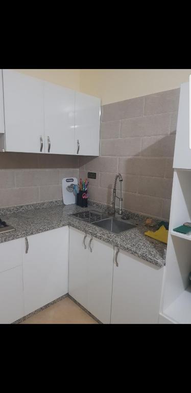 une cuisine avec des armoires blanches et un évier dans l'établissement Havre de paix, à Taourirt