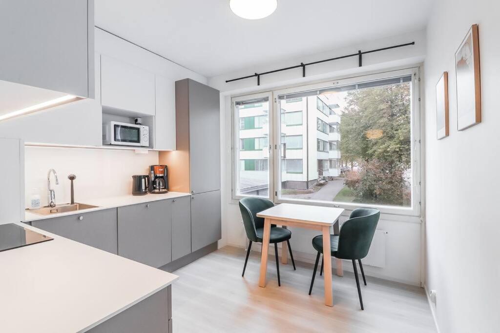 een keuken met een tafel en stoelen en een raam bij Cosy flat with good transport connections and Free parking in Vantaa