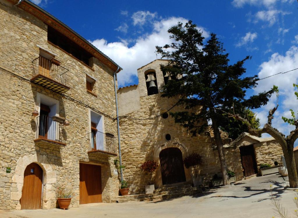 un viejo edificio de piedra con un árbol al lado en Abadia de Cal Bessó en Alberola