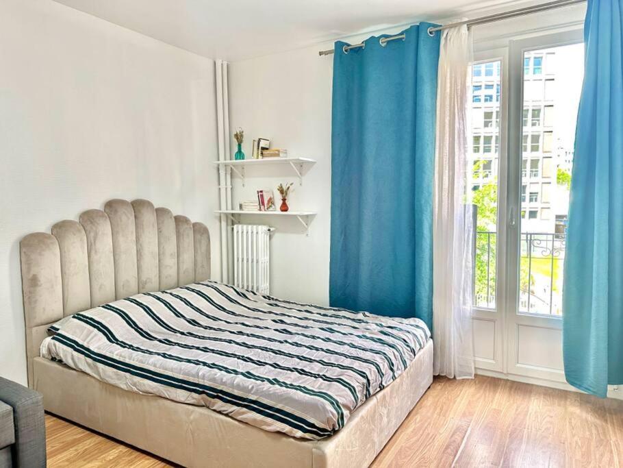 - une chambre avec un lit doté de rideaux bleus et d'une fenêtre dans l'établissement Modern studio near Gare de Lyon Bercy F1, à Paris