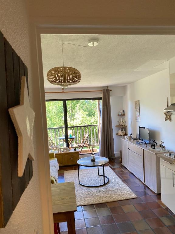 Il comprend une cuisine et un salon avec une table. dans l'établissement Superbe studio terrasse plein sud, à Saint-Chaffrey