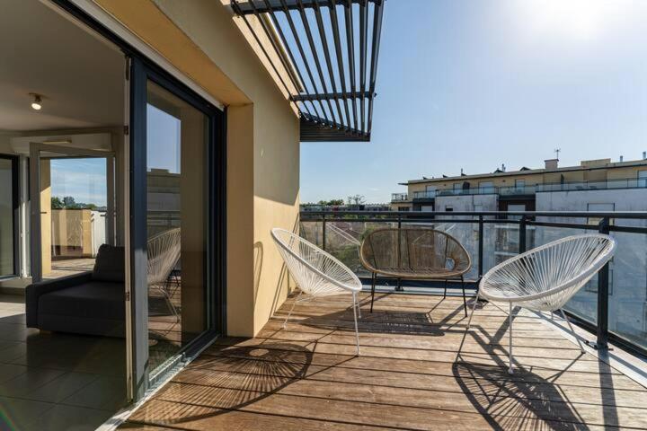 un balcon avec deux chaises et une table sur un immeuble dans l'établissement Bordeaux Mérignac appartement 2 Pièces - 2 Terrasses, à Mérignac