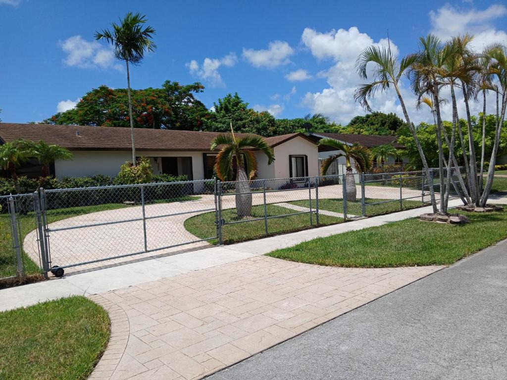 a fence in front of a house with palm trees at Beautiful Miami Home in Miami