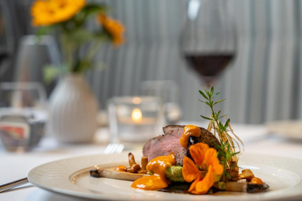 a plate of food on a table with a glass of wine at Hotel Tyrolerhof in Sölden