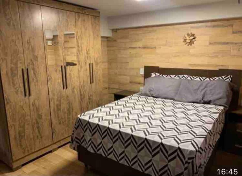 a bedroom with a large bed and wooden cabinets at casa jardim Eliza in Foz do Iguaçu