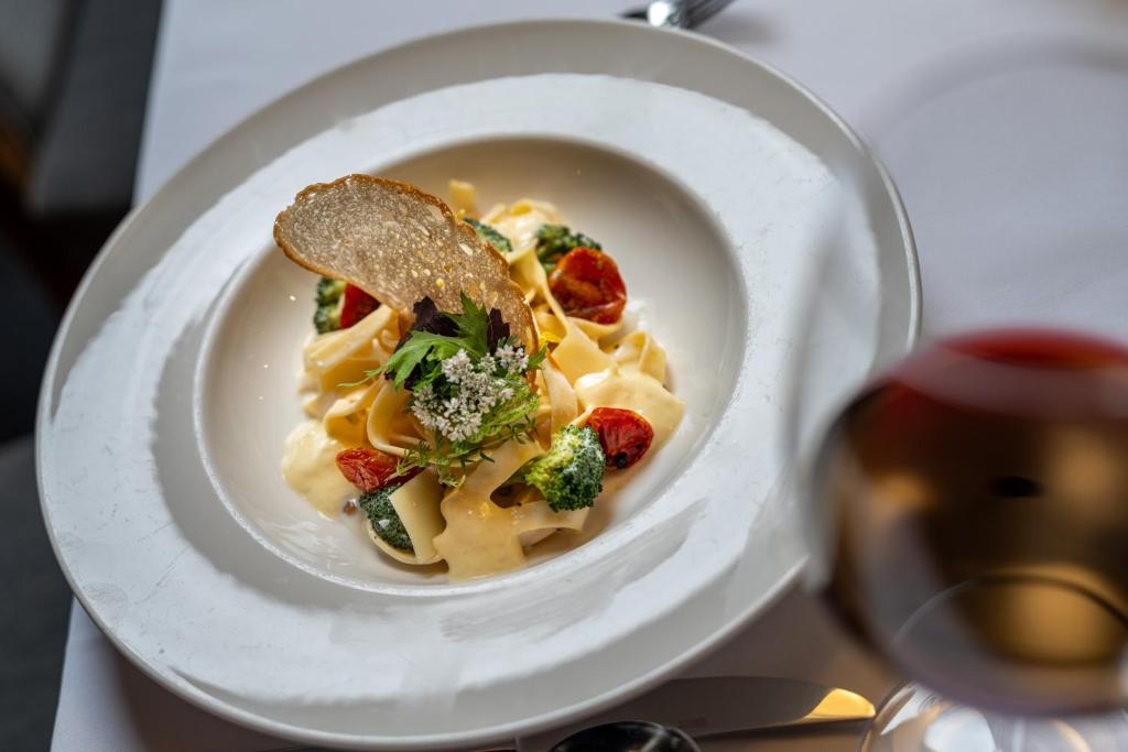 a plate of pasta with broccoli and a piece of bread at Hotel Tyrolerhof in Sölden