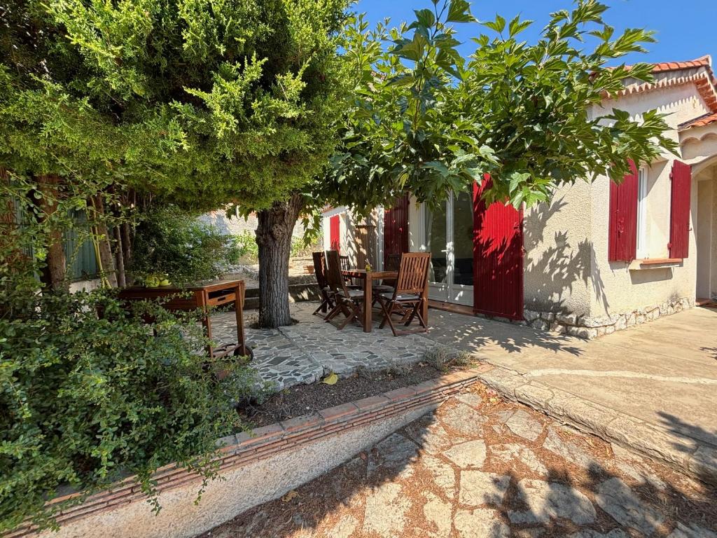 patio ze stołem i krzesłami pod drzewem w obiekcie La Maryse de Cassis w Cassis