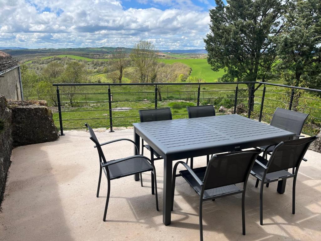 - une table et des chaises noires sur une terrasse avec vue dans l'établissement L'Écrin Champêtre, gîte à la campagne, à Saint-Affrique