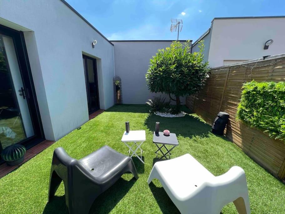 une petite cour arrière avec de l'herbe, des chaises et une clôture dans l'établissement Nantes sud Loire St Sebastien Sur LoireMaison T 2, à Saint-Sébastien-sur-Loire