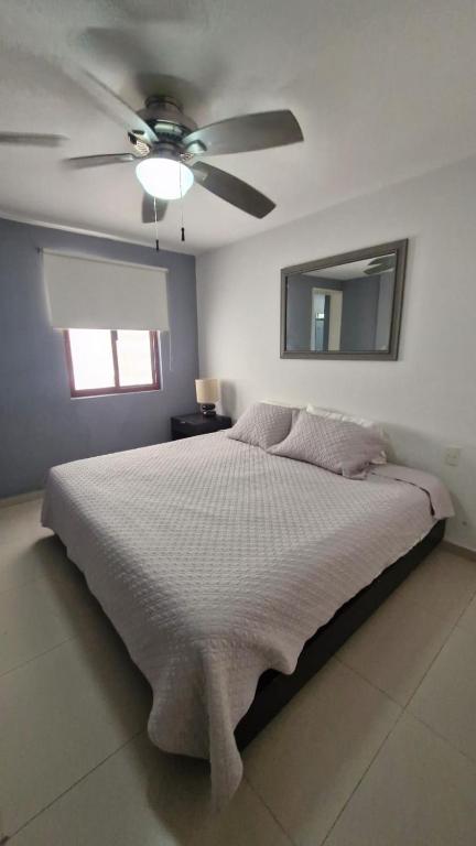 a bedroom with a bed with a ceiling fan at Tranquilidad cerca del mar in Bucerías