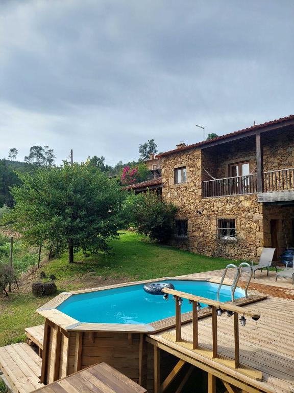 a swimming pool in front of a stone house at Casa da Touça in Celorico de Basto