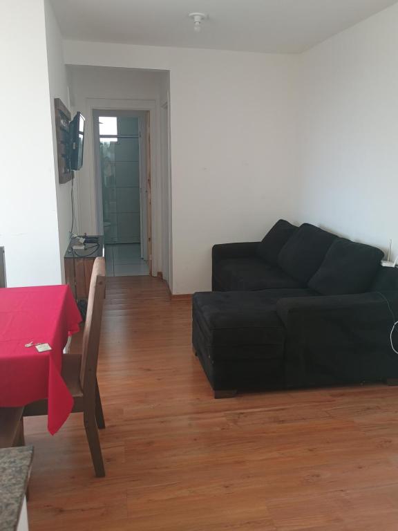 a living room with a black couch and a table at Condomínio ville park collete in Betim