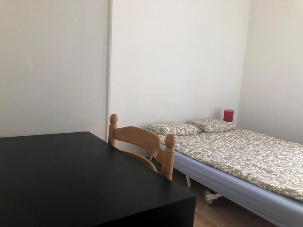 a bedroom with a bed and a table with a chair at Chambre de 9m2 in Bagnolet