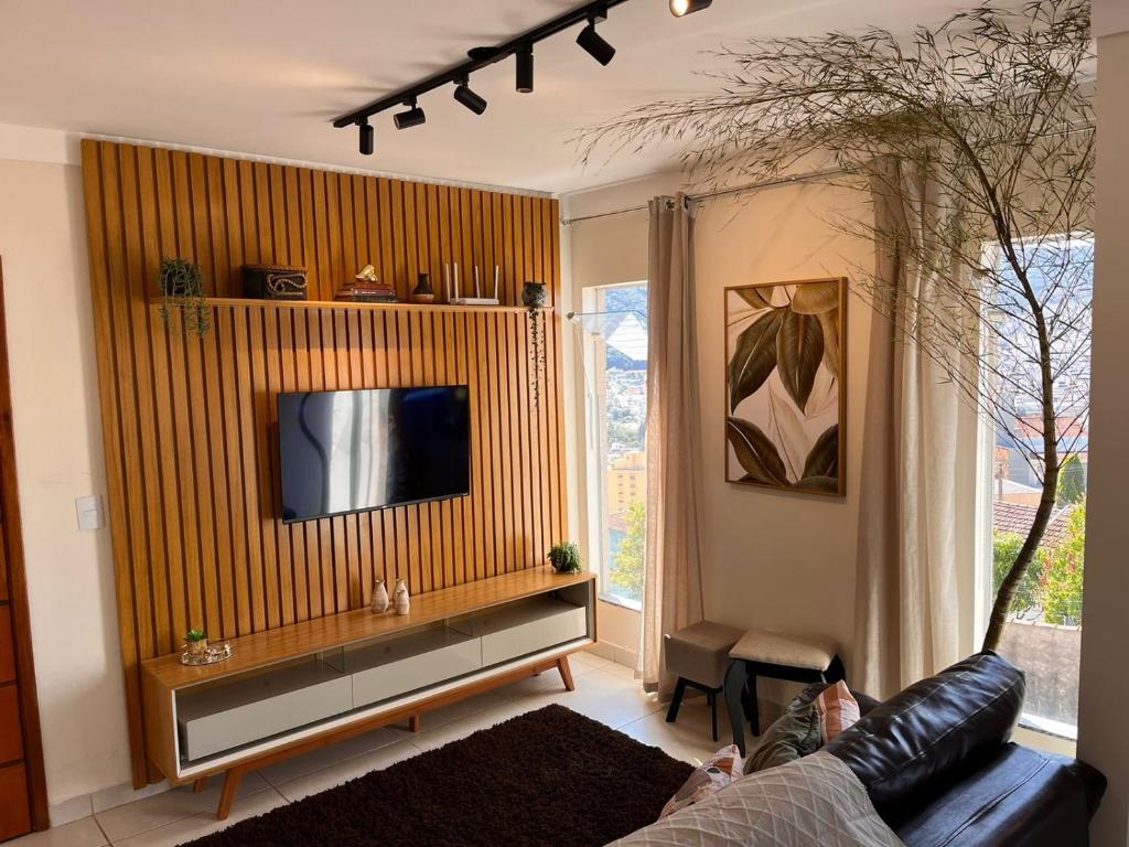 a living room with a couch and a tv at Flat Bambu - Centro - Vista Maravilhosa com Garagem e Elevador in Poços de Caldas