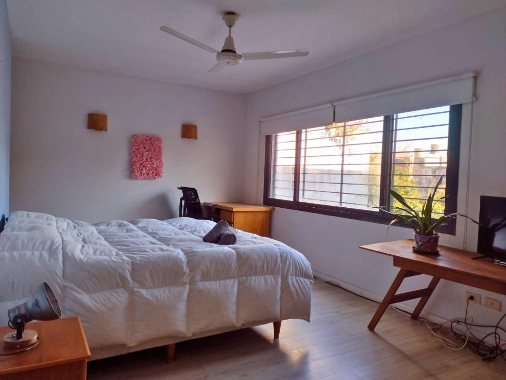 ein Schlafzimmer mit Bett, Schreibtisch und Fenster in der Unterkunft Casa San Isidro pileta jardín parrilla a metros del río in San Isidro