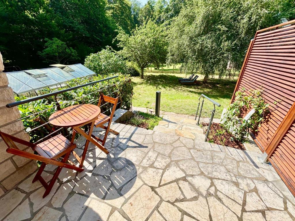 une table et des chaises assises sur une terrasse en pierre dans l'établissement La Forêt - Jardin, Forêt de Fontainebleau, à Bois-le-Roi