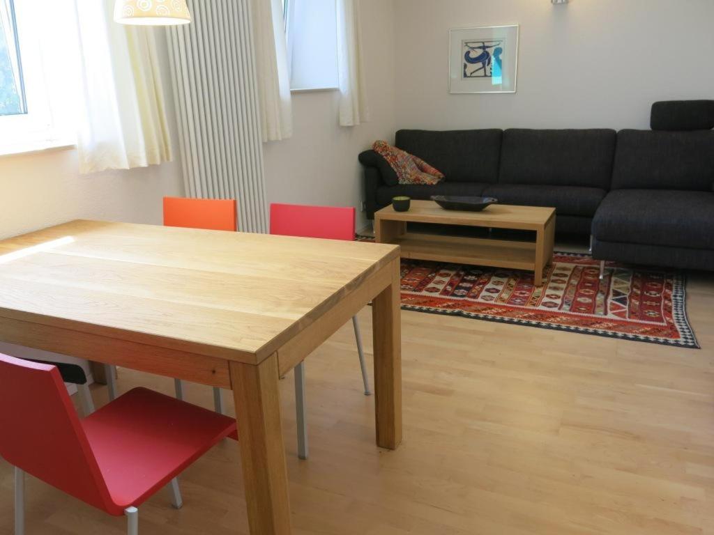 een woonkamer met een houten tafel en rode stoelen bij Zentrales 2-Zimmer Apartment in Tübingen
