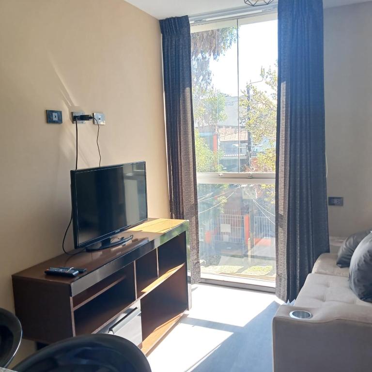 a living room with a tv and a large window at Aparments Av La Paz in Arequipa