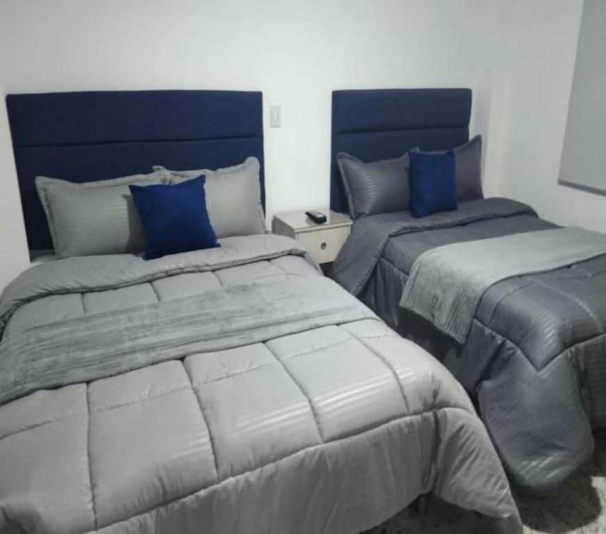 a bedroom with two beds with blue pillows at Céntrico Familiar Vive y disfruta Medellín 107 in Medellín