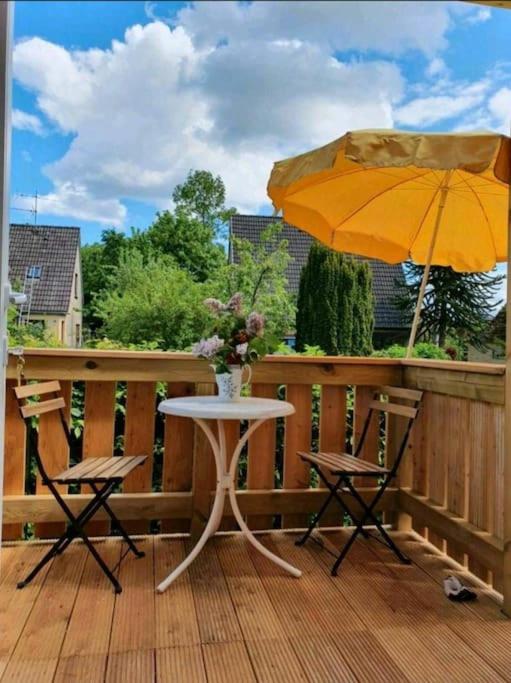 a table and two chairs and an umbrella on a deck at Meerzeitraum Ferienwohnung in Neustadt in Holstein