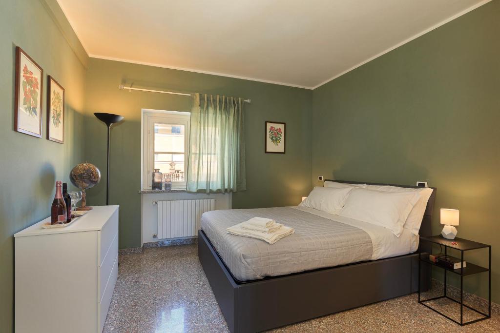 a bedroom with a bed with green walls and a window at Casa del Corso in Novi Ligure