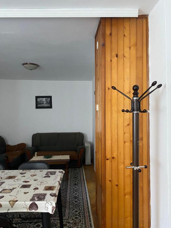 a living room with a table and a wooden door at Sunlit City Apartment Gjakova in Gjakove