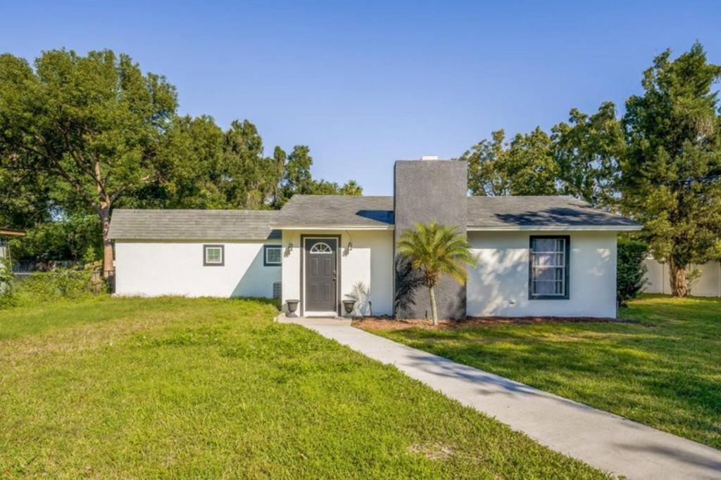 a white house with a palm tree in the yard at Relax & Unwind 1br Retreat Wpool Access & Wi-fi in Orlando