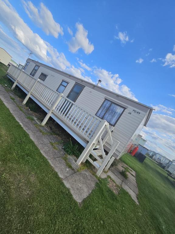 un mobile home avec une terrasse couverte sur la pelouse dans l'établissement Golden Anchor 8b9 Caravan Park Holiday Home, à Chapel St. Leonards
