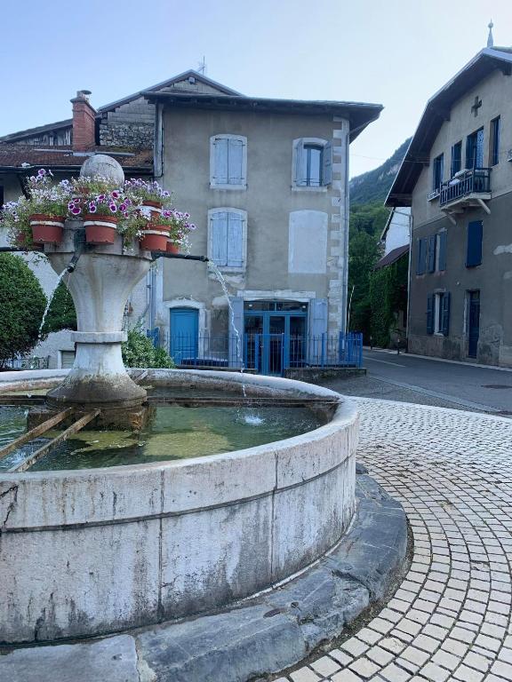une fontaine fleurie devant un bâtiment dans l'établissement Maison chaleureuse au cœur du Grésivaudan, à Barraux