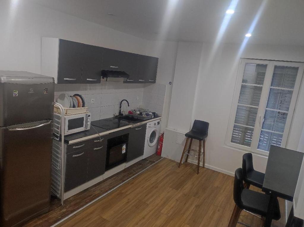 une petite cuisine avec un réfrigérateur et un micro-ondes dans l'établissement TRES BEL APPARTEMENT AUX PIEDS DE LA GARe, à Épinay-sur-Seine