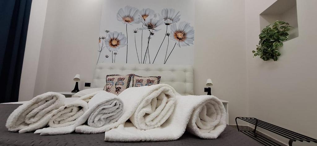 een bed met witte dekens en bloemen erop bij Lilly apartment in Catania
