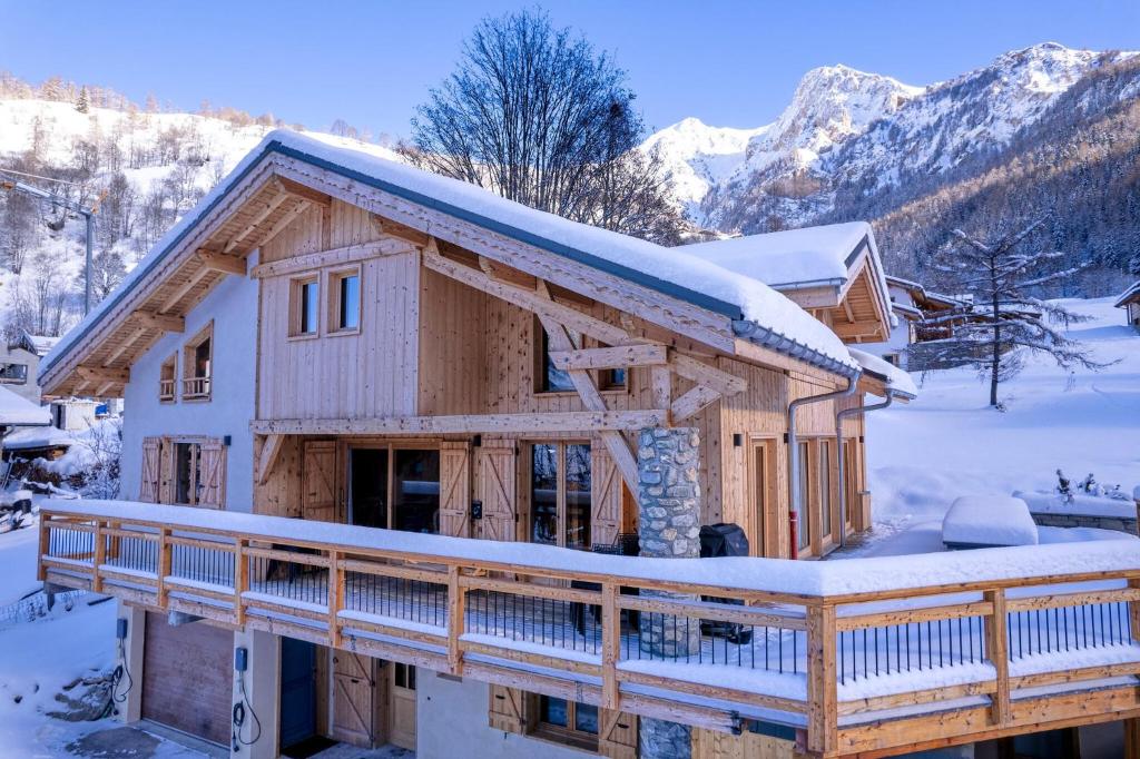 une cabane en rondins dans la neige avec des montagnes enneigées dans l'établissement Chalet les Niverolles PARADISKI, à Peisey-Nancroix